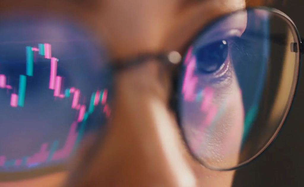 Close-up of a person's eye wearing glasses, with a reflection of colorful data charts on the lenses, symbolizing data analysis and visualization